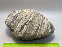 a stream cobble showing green, bluish gray, and white thin crystal banding